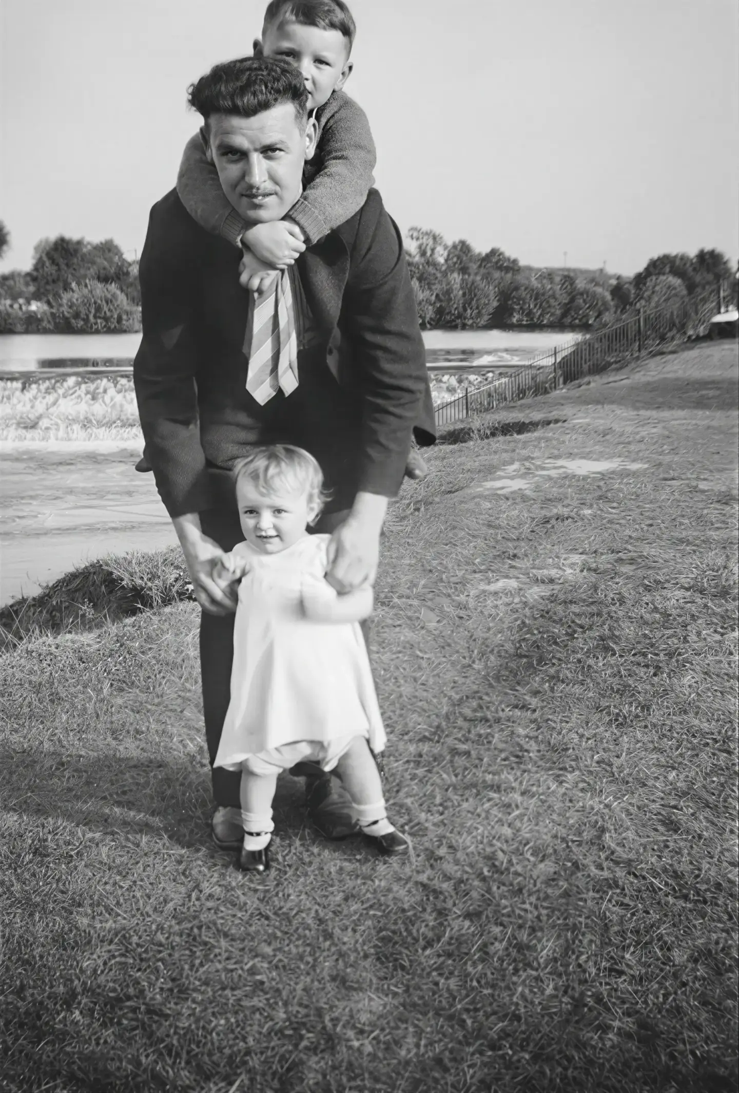 Repaired black-and-white outdoor family photo of a man with two children after online AI restoration