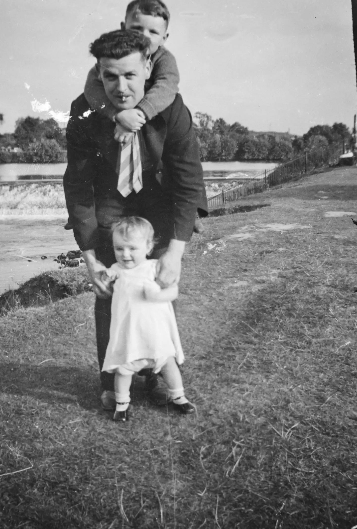 Damaged black-and-white outdoor family photo of a man with two children before online AI repair